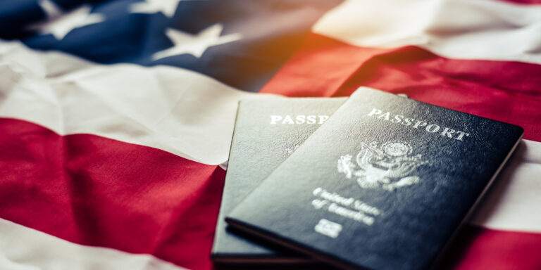 Dos pasaportes estadounidenses sobre una bandera estadounidense que simbolizan la ciudadanía.