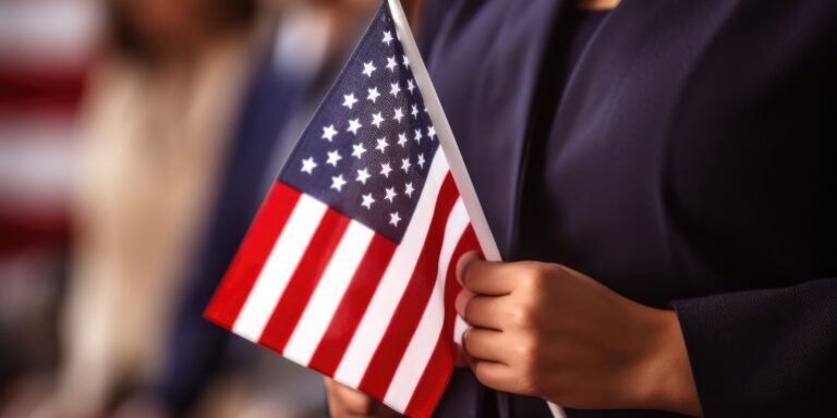 Person holding a small American flag during a U.S. citizenship ceremony, symbolizing the 2025 citizenship test changes.