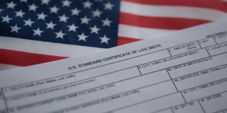 Formulario de solicitud de certificado de nacido vivo junto a la bandera de Estados Unidos. Concepto de ciudadanía por derecho de nacimiento.
